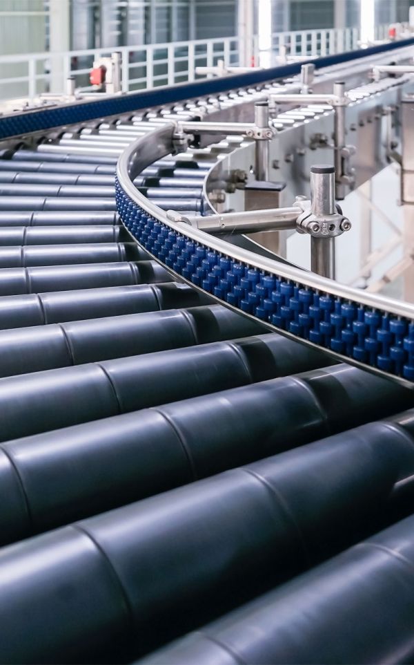 Detailaufnahme eines modernen Rollenförderers mit seitlich laufender Zahnriemenführung in einer Kurve